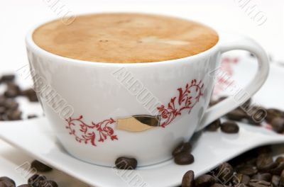 Cup of coffee and grains over white