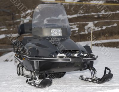 Black snowmobile in winter mountains close up