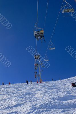 Chairlifts & skiers, against blue sky