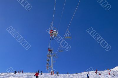 Chairlifts & skiers, against blue sky