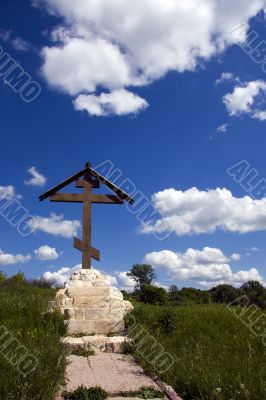 Orthodox cross over meadow and blue sky