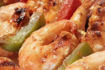 Grilled prawns on bamboo sticks served in dinner setting. Macro