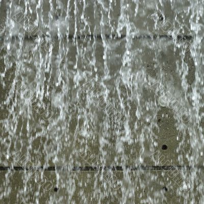 park waterfall with concrete wall behind