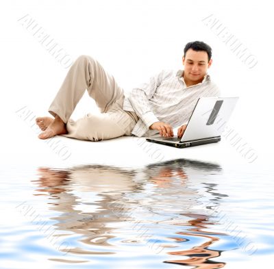 relaxed man with laptop on white sand