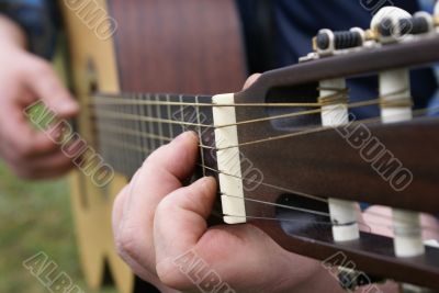 man`s fingers playin guitar