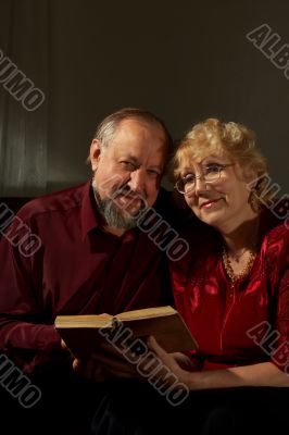 Happy elderly spouses behind reading