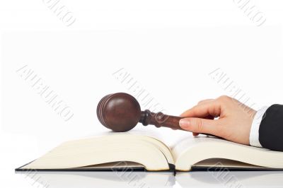 Holding a wooden gavel over the law book