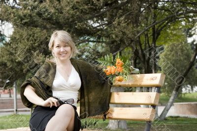 Women with bunch of flowers at the bench in park