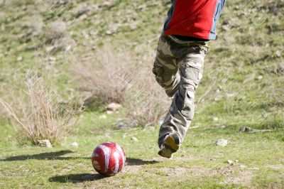 Men teens playing soccer in green grass