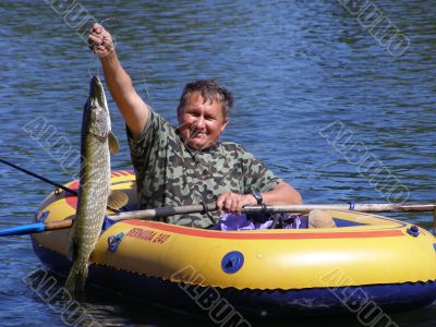 The fisherman in the boat with a pike.