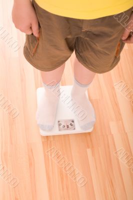 Boy measures weight on floor scales