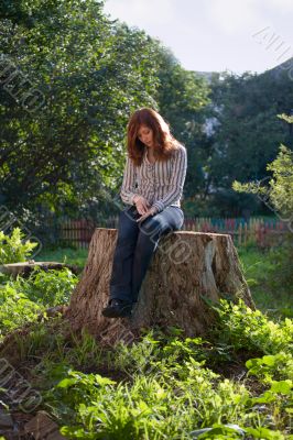 Young sad melancholic woman sit on big stub