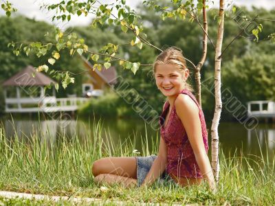 Young smiling girl on the coast of a pond