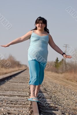 Girl Balancing On Railroad Tracks