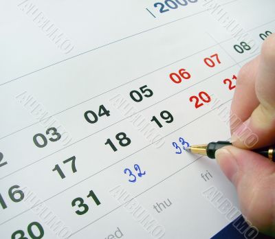 Hand with a pen, adding numbers in a calenda