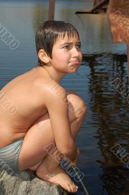 boy sitting near water