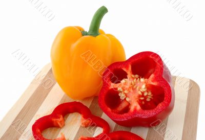 Red and yellow paprika on bamboo cutting board.