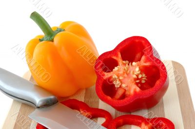 Red and yellow paprika on bamboo cutting board.