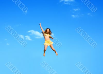 The happy jumping girl on a background of the blue sky