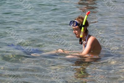 Young woman sitting in water with snorkel and fins