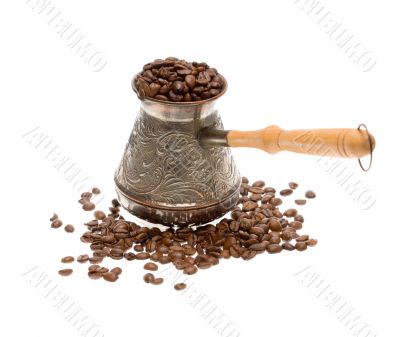 Cezve with freshly roasted coffee beans over white background