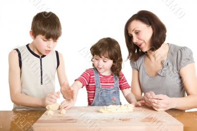 mother and children in the kitchen making a dough
