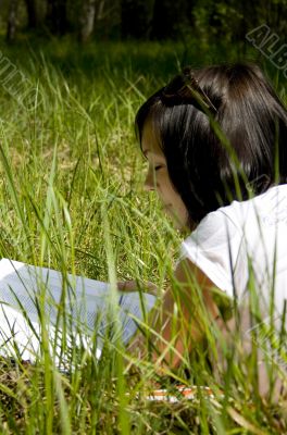 pretty young girl reading on the grass