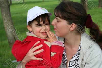 little girl with her mother in the spring park kissing