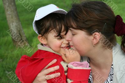 little girl with her mother in the spring park kissing