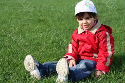 little girl in the park sitting on green grass
