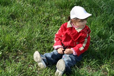 little girl in the park sitting on green grass