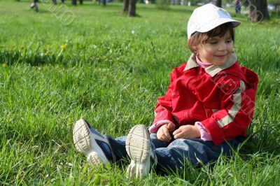 little girl in the park sitting on green grass