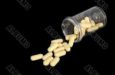 Yellow pills spilling out of a bottle