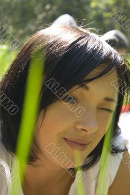 Beautiful young girl among green grass
