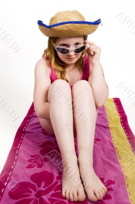 young girl on towel looking over her sunglasses