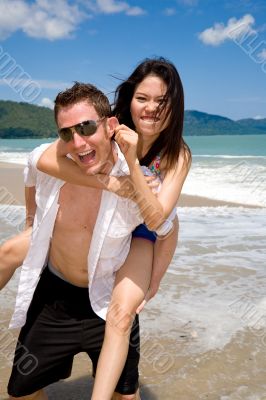 playful couple at the beach pulling ears