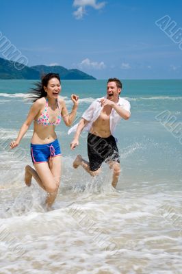 couple racing on the beach with joy