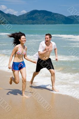 couple racing on the beach with joy