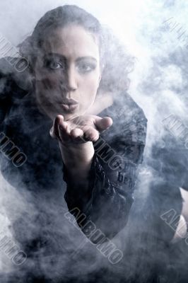 Woman with long curly hair blowing smoke