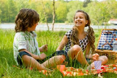 Two kids smiling while picknicking