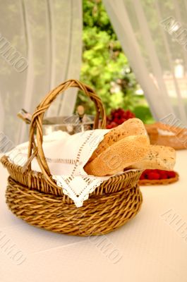 Table setting with bread basket with wine bottles on background