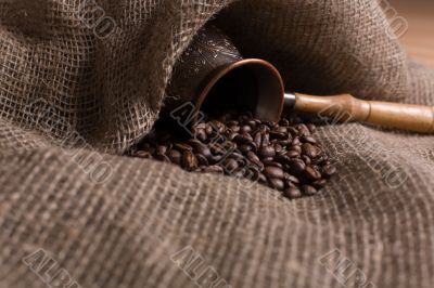 Cezve with freshly roasted coffee beans on sackcloth
