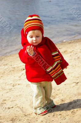 Girl plays with sand on coast of lake