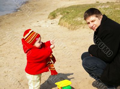 Daddy with a daughter play with sand