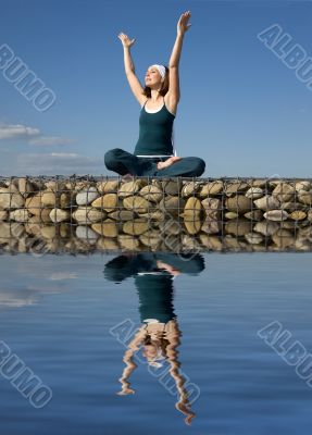 A woman doing yoga on a stone above  water