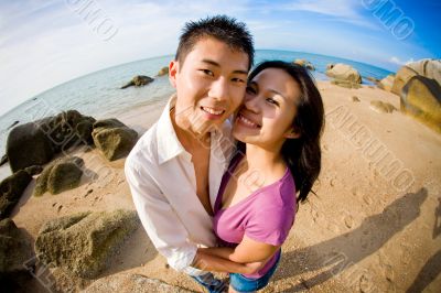 happy couple smiling on the camera by the beach