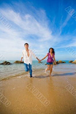 happy couple holding hands having fun running on the beach