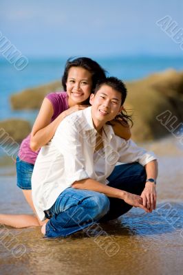 young couple squating by the beach happily