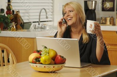 Woman in Kitchen on Cell Phone & Laptop