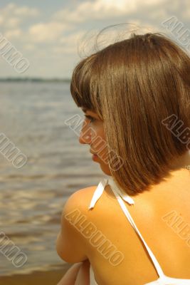Attractive girl sitting and contemplating aloun near the river